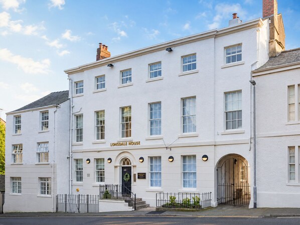 Un bâtiment blanc avec une enseigne indiquant « LONSDALE HOUSE » et un portail noir.