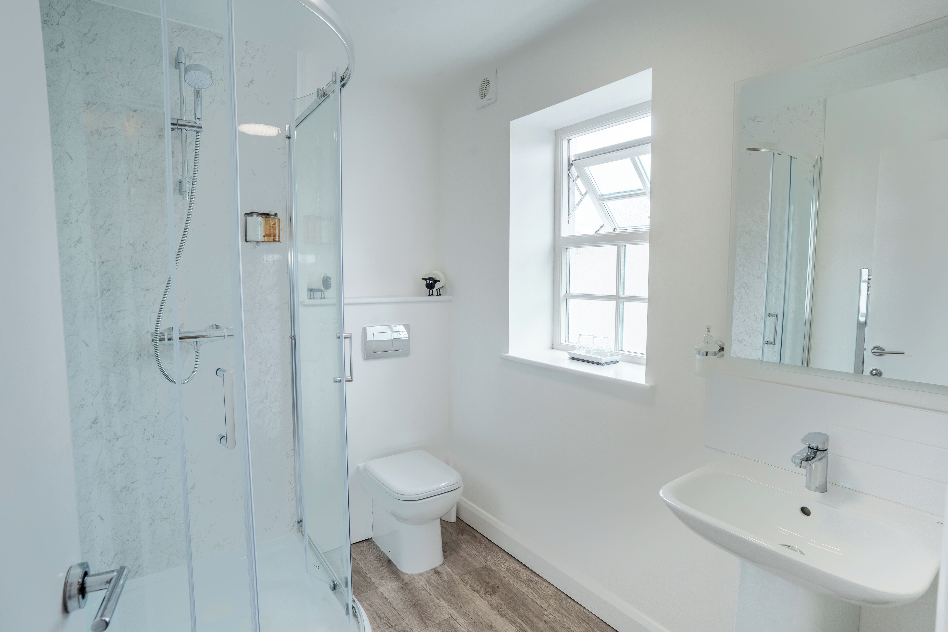 Ein modernes Badezimmer mit einer Duschkabine, einer Toilette und einem Waschbecken mit Spiegel darüber.