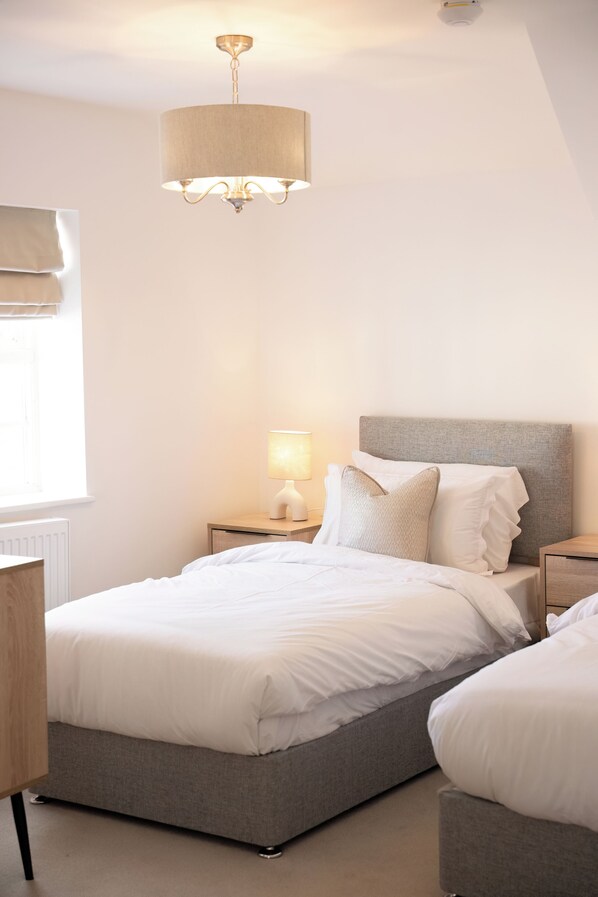 Ein Schlafzimmer mit einem Bett, Nachttischen, einer Lampe und einer Deckenleuchte.