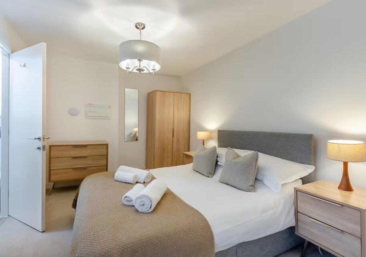 Ein modernes Hotelzimmer mit einem großen Bett, Nachttischen, einem Kleiderschrank und einer Kristallleuchtre.