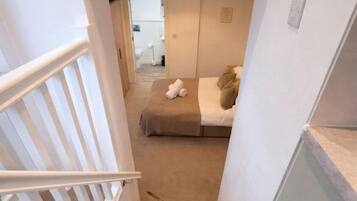 A dog on a carpeted staircase in a room with a bed and a hanging light fixture.