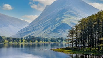A serene lake with mountains in the background and a forested area with people enjoying the view.