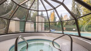 Una piscina interior amb sostre de vidre, envoltada de terres de rajola i baranes metàl·liques.