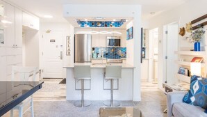 A modern kitchen with a central island, white cabinetry, and a blue hexagonal backsplash.