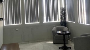 A modern living room with a sofa, a small round table, and a TV mounted on the wall. - AB Bed and breakfast  (Chihuahua)