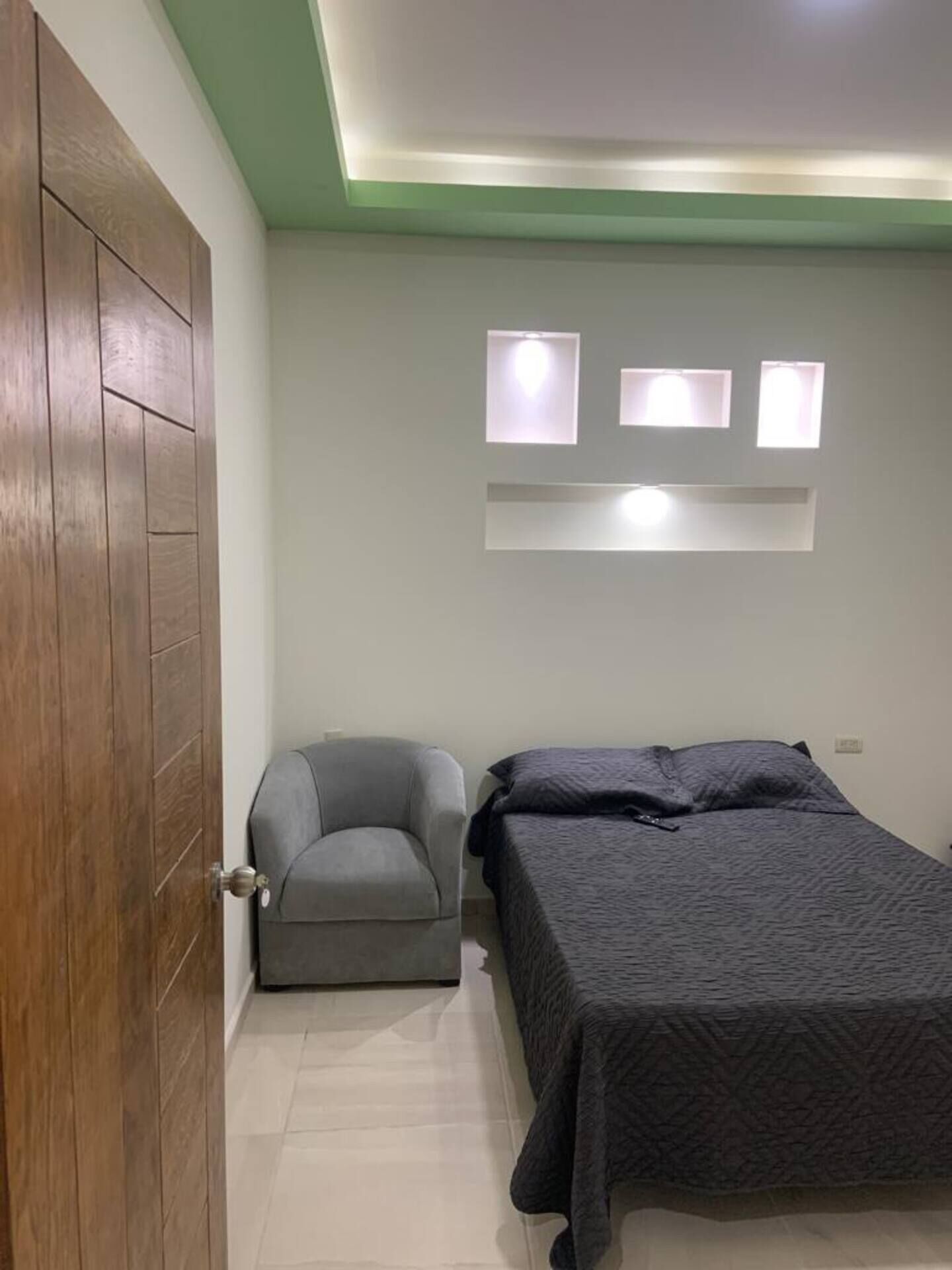 Un dormitorio con cama, una silla y un armario de madera.
