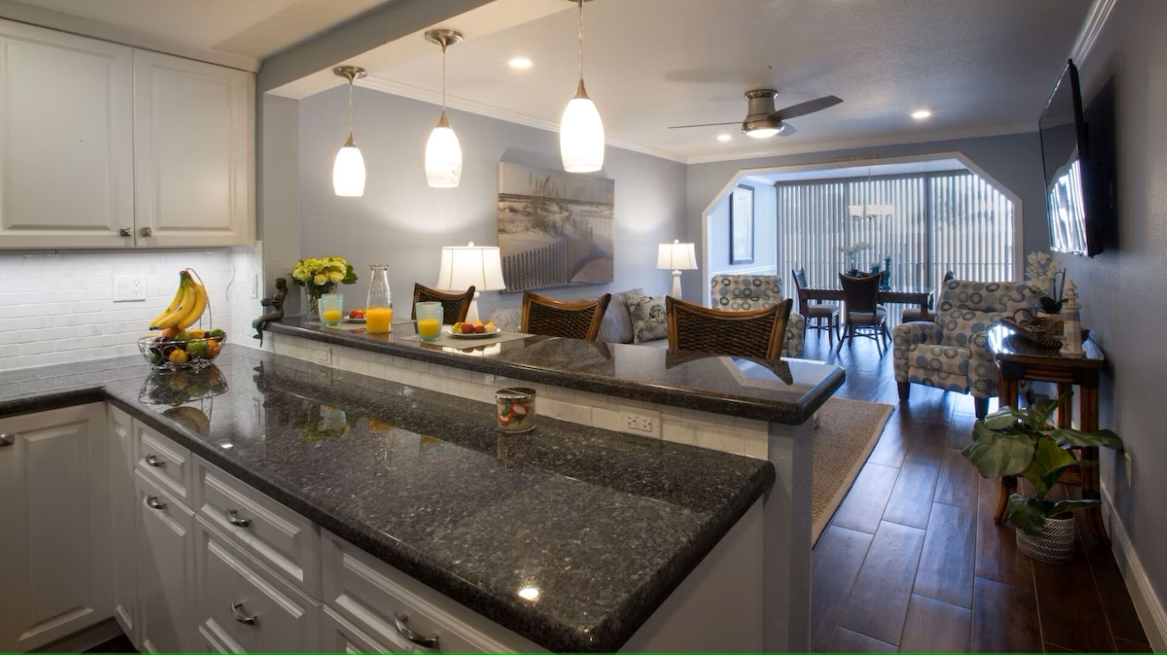 A kitchen with granite countertops, white cabinets, and a dining area with a view.
