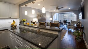 Una cocina con encimeras de granito, armarios blancos y un comedor con vistas.