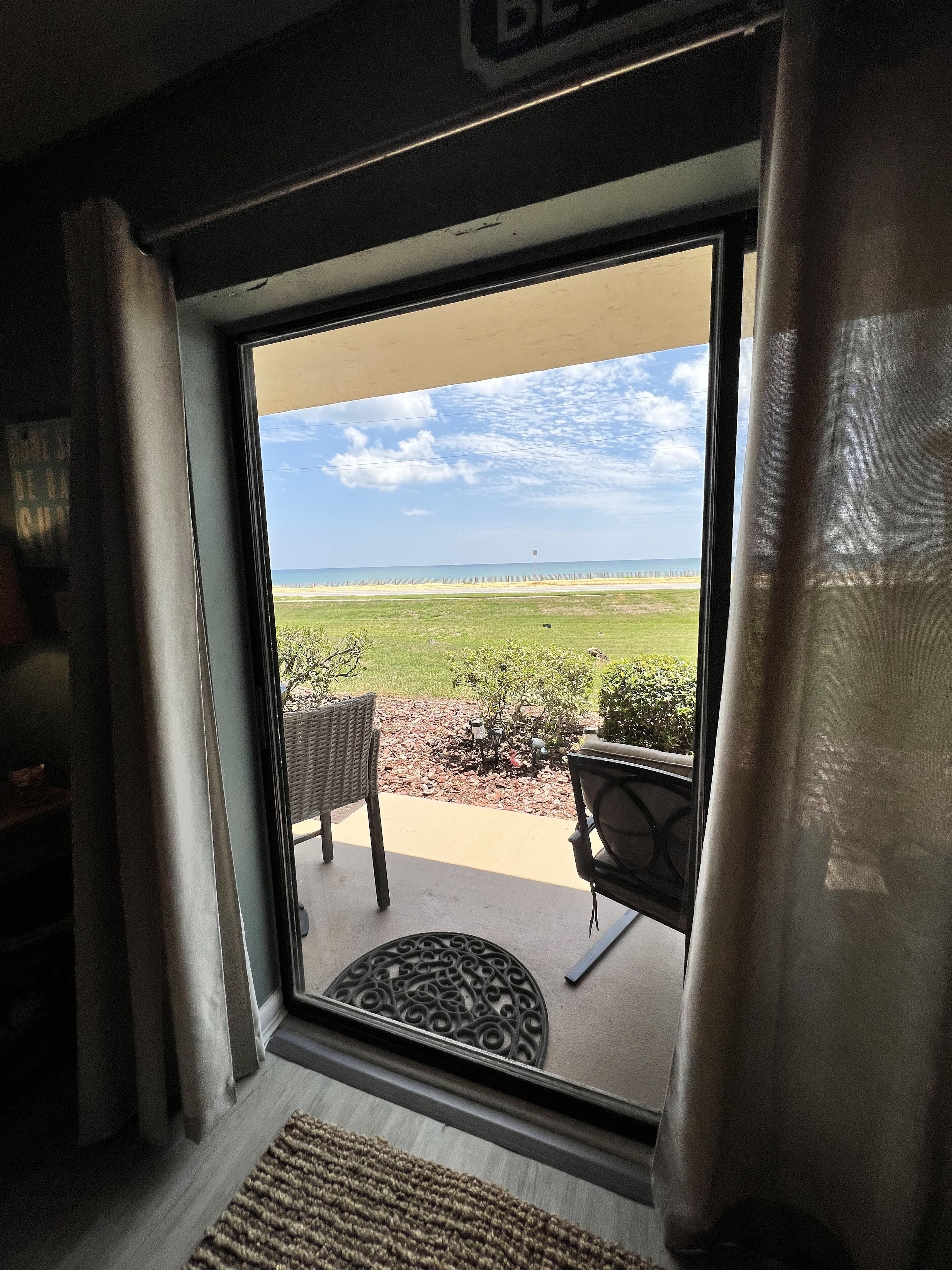 A view from inside a room with a window overlooking a grassy area and a clear sky.