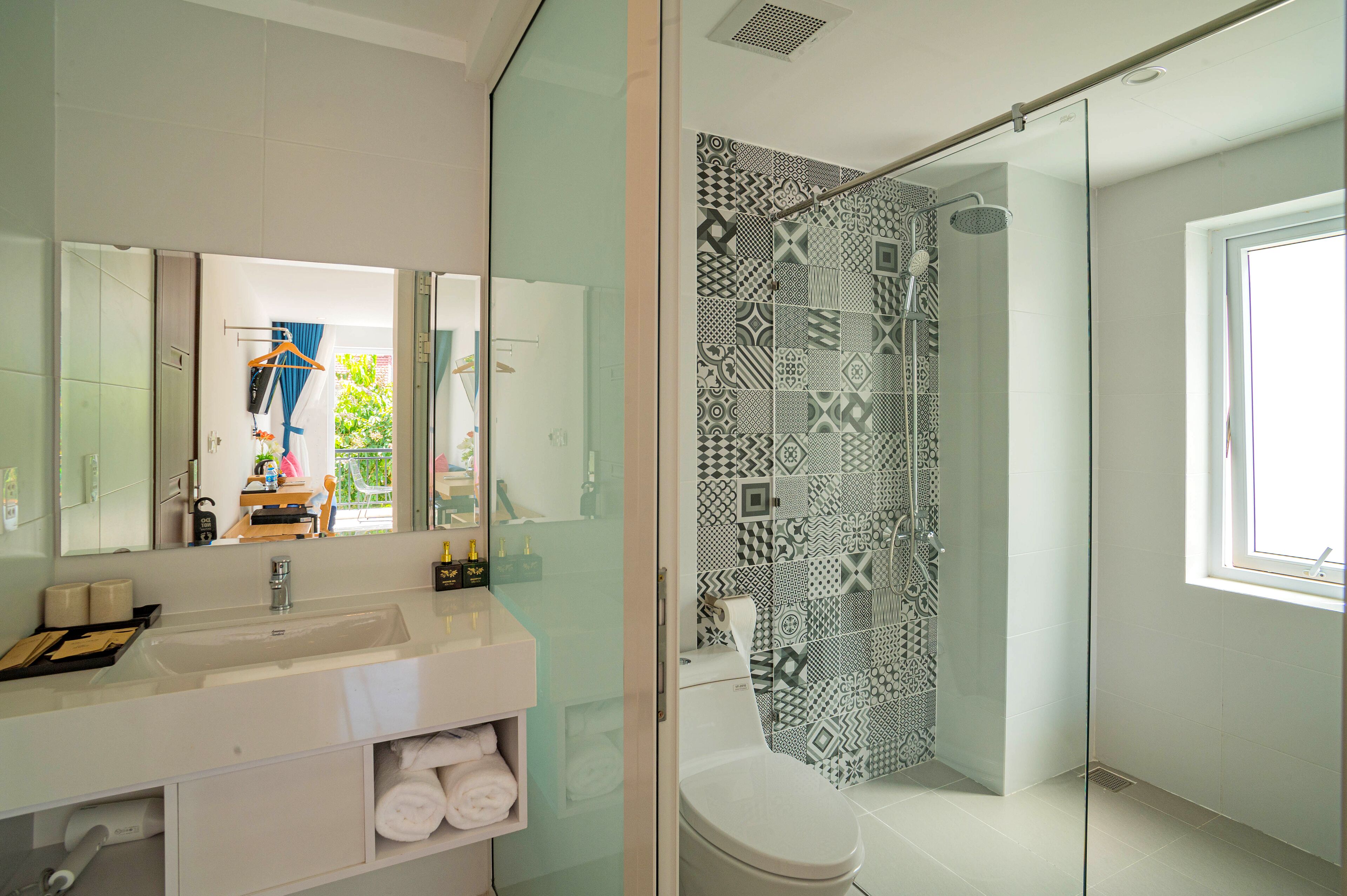 A modern bathroom with a glass shower enclosure, a white sink, and a large mirror.