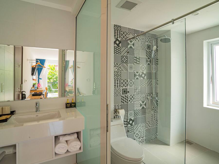 A modern bathroom with a glass shower enclosure, a white sink, and a large mirror.