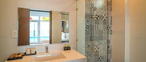 A modern bathroom with a large mirror, a white sink, and a shower with patterned tiles.