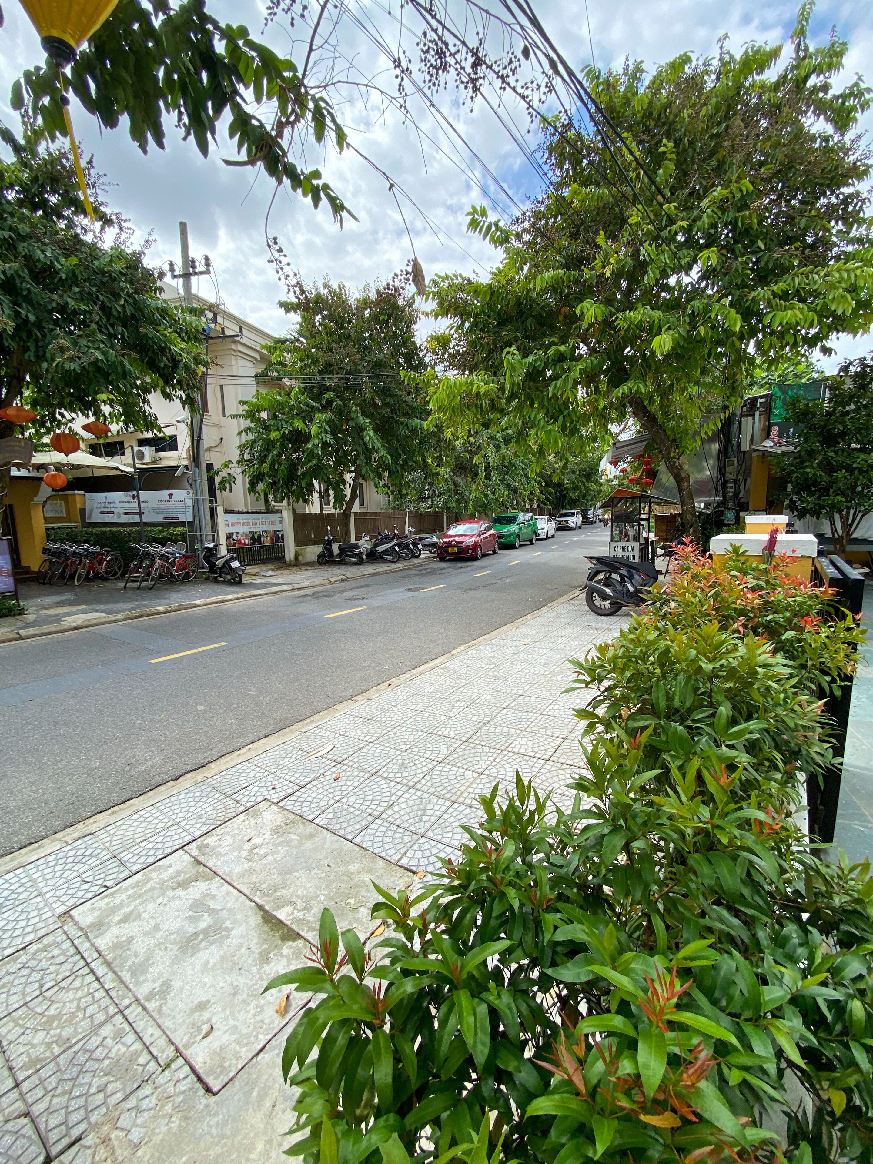 A street view with a sidewalk, parked motorcycles, and cars.