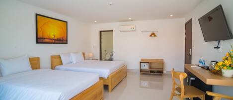 A hotel room with two wooden beds, a desk with a chair, a flat-screen TV, and a painting on the wall.