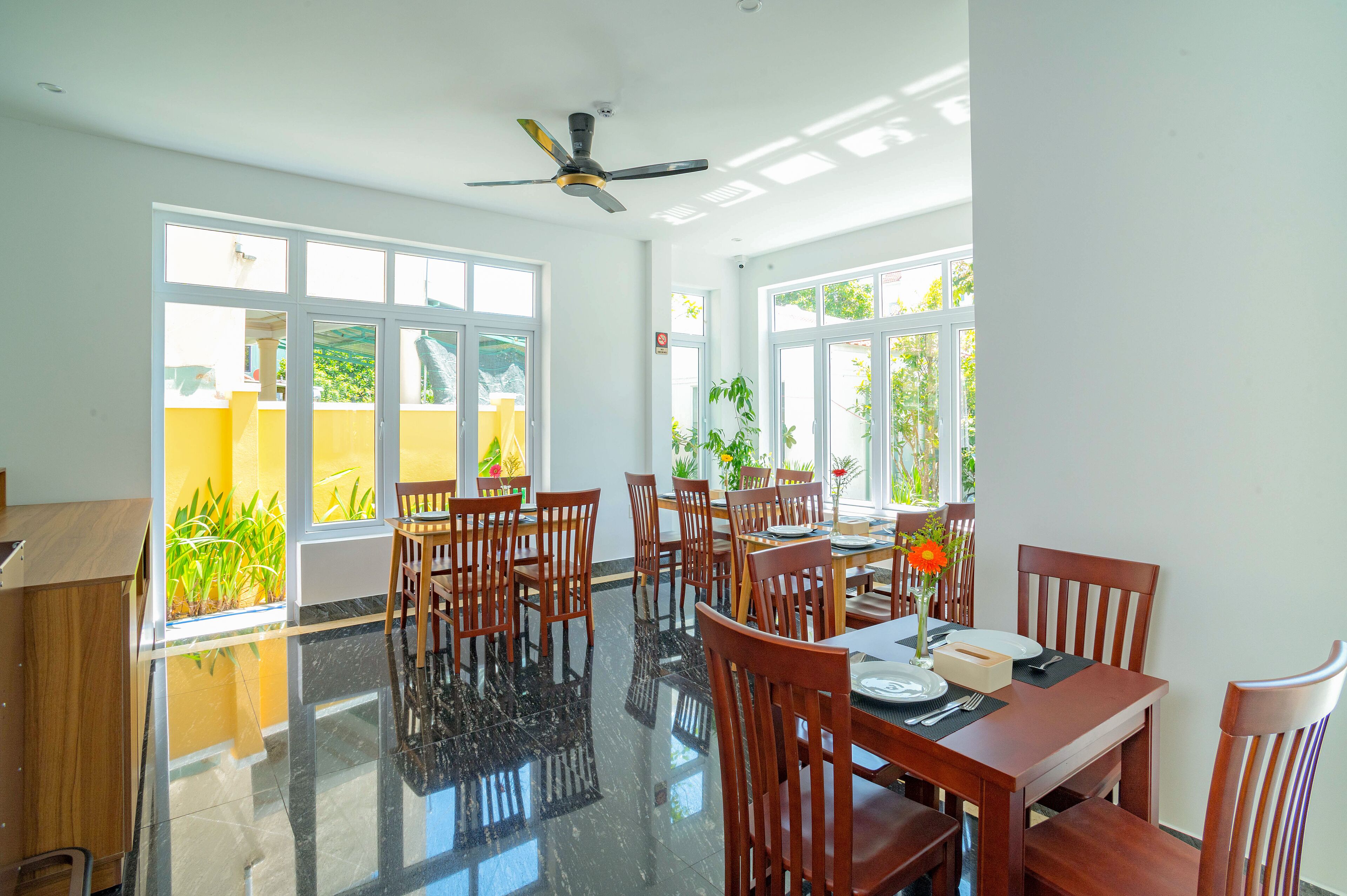 A dining area with a polished floor, wooden chairs, a table set for dining, and large windows allowing natural light.