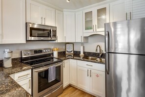 A modern kitchen with stainless steel appliances, white cabinetry, and granite countertops. - Charming PCB Condo w/ Balcony: Walk to Beach! (Panama City Beach)