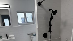 A modern bathroom with a shower, toilet, and sink.