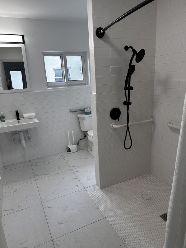 A modern bathroom with a shower, toilet, and sink.
