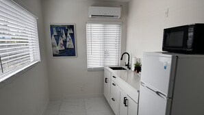 A kitchen with white cabinets, a white refrigerator, a microwave, a sink, and a painting of sailboats.