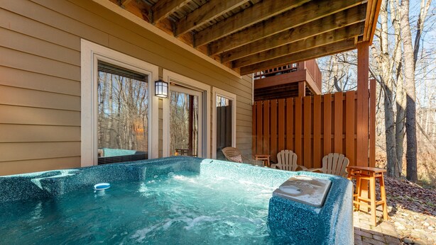 A hot tub with a wooden deck and chairs, surrounded by a wooden fence and trees. - Cozy Dog Friendly Retreat w/ Hot Tub & Views (McHenry)
