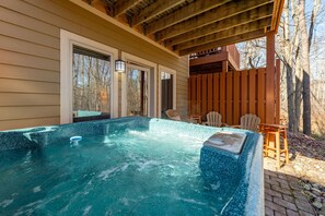 A hot tub with a wooden deck and chairs, surrounded by a wooden fence and trees. - Cozy Dog Friendly Retreat w/ Hot Tub & Views (McHenry)