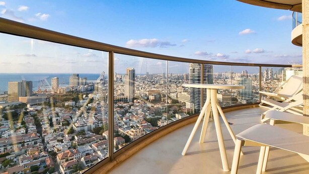 A high-rise balcony with a panoramic city view, a small table, and two lounge chairs. - Blanche Eilat (Tel Aviv)