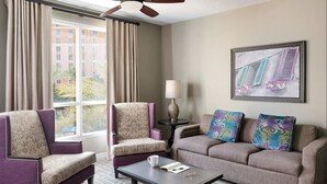 Ein Hotelzimmer mit zwei Sesseln, einem Sofa, einem Couchtisch und einem Bild an der Wand.