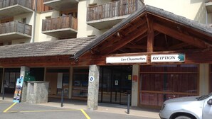A reception area with a wooden facade, a sign reading "Les Chaumettes," and a car parked in front. - Equipped apartment in Superdévoluy (Le Devoluy)