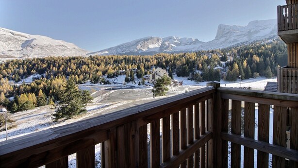 A wooden deck overlooking a mountainous landscape with snow-covered ground and trees. - Equipped apartment in Superdévoluy (Le Devoluy)