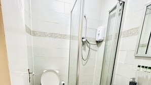 Et badeværelse med toilet, bruseniche og håndvask.