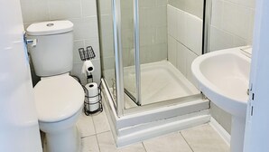Et badeværelse med bruseniche, toilet og håndvask.