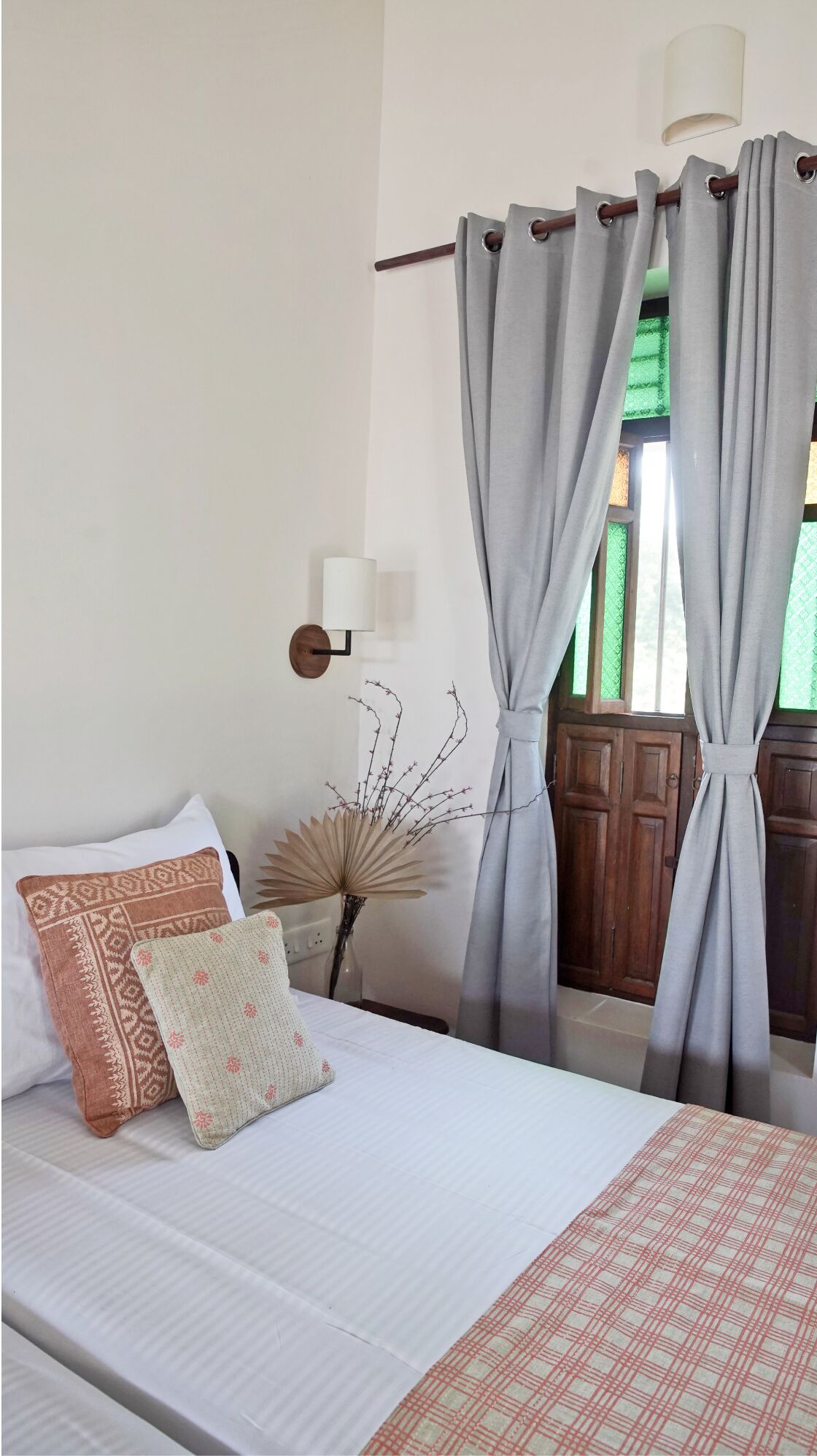 A bedroom with a bed, pillows, a bedside lamp, and curtains.