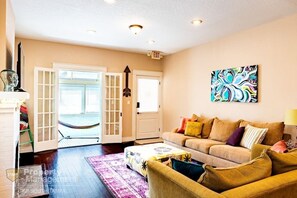 Relax in the stylish living room with a comfortable sofa, colorful artwork, and a large window offering a view.