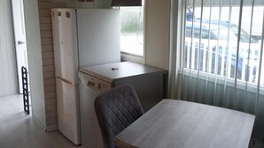 A compact kitchen with a refrigerator, a small countertop, and a window with a view of parked cars. - Captivating 1-bed Chalet in Newquay (Newquay)