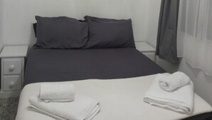 A neatly made bed with dark bedding, a white pillow, and a folded towel on the bed. - Captivating 1-bed Chalet in Newquay (Newquay)
