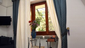 A room with a window, a chair, a small table, and a vase with flowers. - B&B Royal Reggia di Caserta (Casagiove)