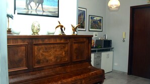 A wooden reception desk with a mounted television, framed artwork on the wall, and a door to the right. - B&B Royal Reggia di Caserta (Casagiove)