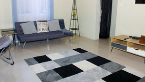 A living room with a sofa, a tall floor lamp, a wooden TV stand, and a patterned rug. - Peaceful Retreat (Discovery Bay)