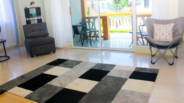 A living room with a checkered rug, a grey sofa, and a folding chair. - Peaceful Retreat (Discovery Bay)