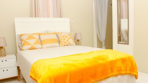 A neatly made bed with a bright orange blanket, white bedding, and patterned pillows. - Peaceful Retreat (Discovery Bay)
