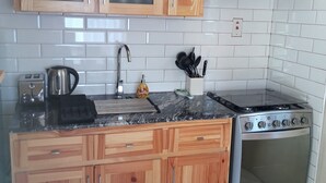 A kitchen with wooden cabinets, a stainless steel stove, and a tiled backsplash. - Peaceful Retreat (Discovery Bay)
