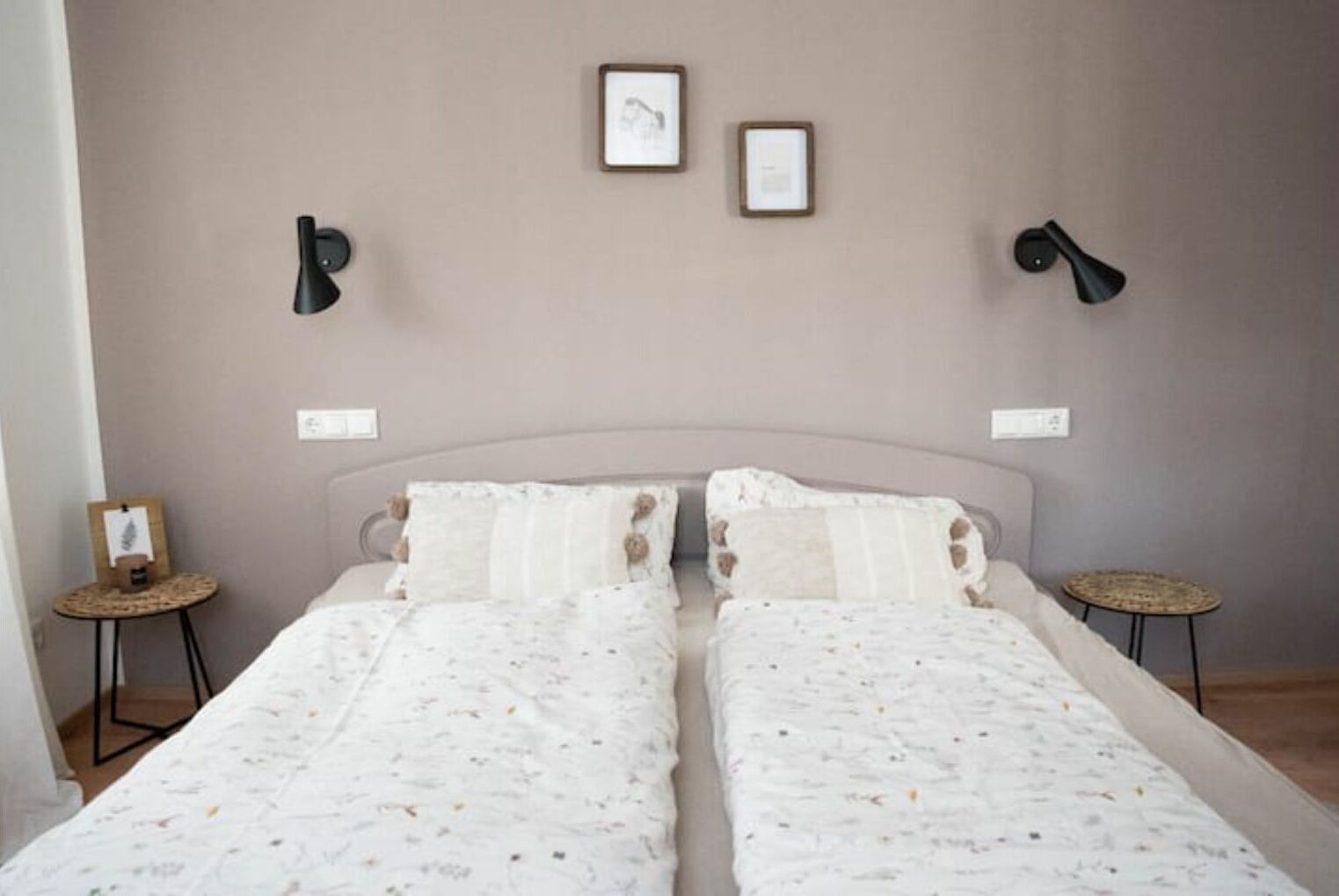 Ein Doppelbett mit floralem Überwurf, zwei Nachttische und Wandlampen.