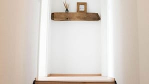 Eine Treppe mit Holzbeschlägen und schwarzen Kanten, die zu einer Zwischenebene führt, auf der sich ein kleines gerahmtes Bild und ein dekoratives Objekt befinden.
