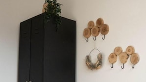 Ein Zimmer mit einem schwarzen Kleiderschrank, einem gewebten Korb und Holzdekorationen an der Wand.