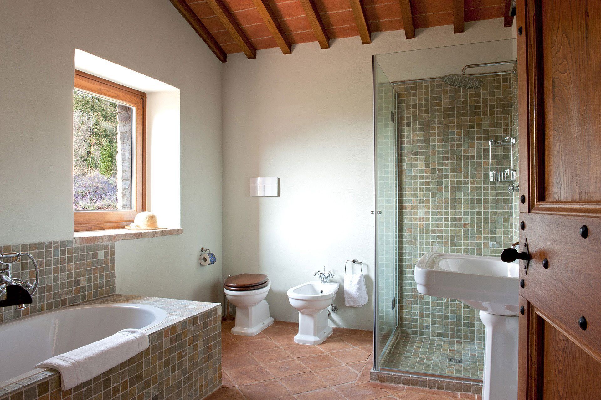 Un baño con bañera, inodoro, bidé y cabina de ducha de vidrio.
