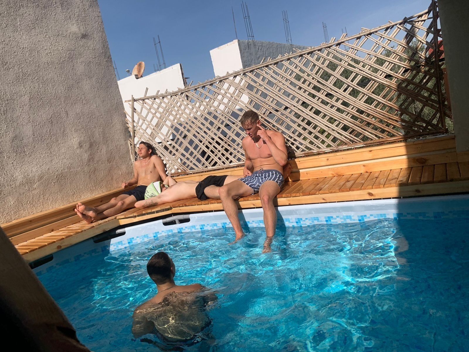 A poolside area with wooden deck seating and a pool.