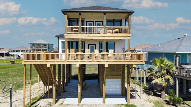 A two-story beachfront house with a wooden deck, a covered lower level, and a garage. - 7 Day Weekend: 4  BR, 3  BA House in Crystal Beach, Sleeps 17 (Bolivar Peninsula)