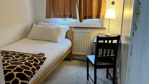 A small, cozy room with a single bed, a chair, a table, and a window with curtains. - South London Single Bedroom in Mitcham (Mitcham)