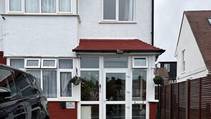 A two-story house with a red roof, white exterior walls, and a front door with glass panels. - South London Single Bedroom in Mitcham (Mitcham)