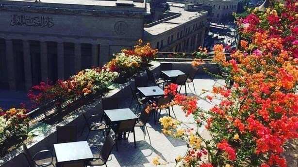 An outdoor seating area with tables and chairs, surrounded by vibrant flowers. - Carlton Downtown Cairo (Cairo)